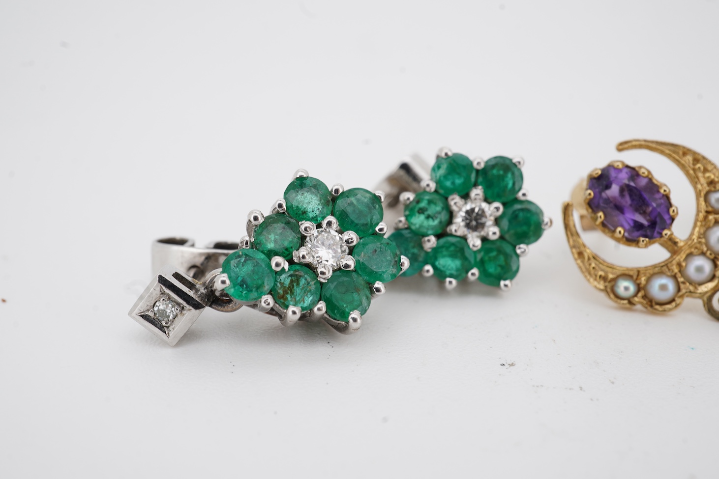 A pair of mid to late 20th century white metal, emerald and diamond cluster set drop earrings, drop 16mm, together with a pair of 9ct gold, amethyst and seed pearl set crescent drop earrings.